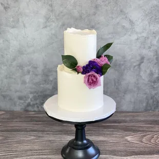 Simple cake with royal edges on both tiers. Mauve purple rosebuds in the center.