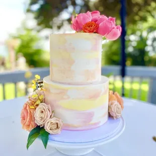 Watercolor wedding cake  tiers with hues of yellow and pink, natural flower embellishment