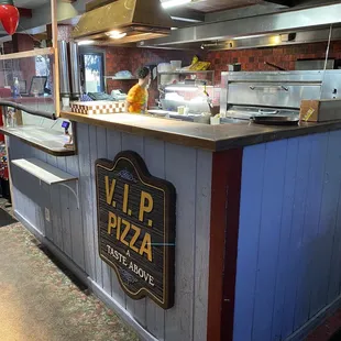 a restaurant counter with a sign that says vip pizza