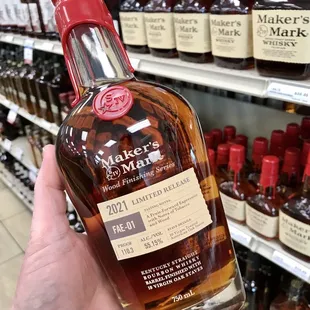 a hand holding a bottle of maker&apos;s mark