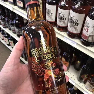a hand holding a bottle of bourbon