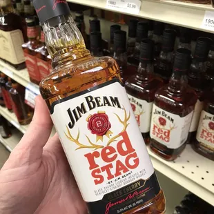a hand holding a bottle of jim beamt red stag