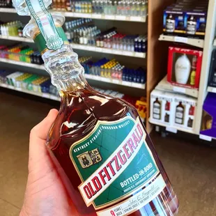 a hand holding a bottle of bourbon