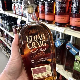 a hand holding a bottle of elijah craig bourbon