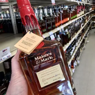 a hand holding a bottle of maker's mark
