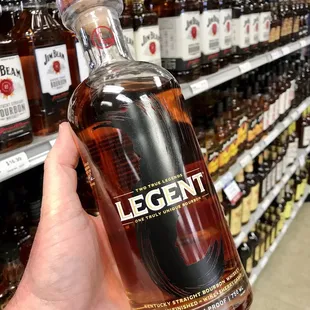 a hand holding a bottle of legend