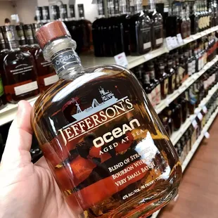 a hand holding a bottle of jefferson's oscar