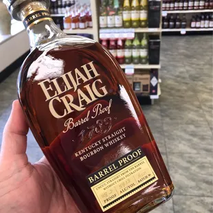 a hand holding a bottle of elijah craig bourbon