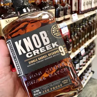 a hand holding a bottle of knob creek bourbon