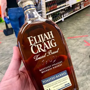 a person holding a bottle of elijah craig