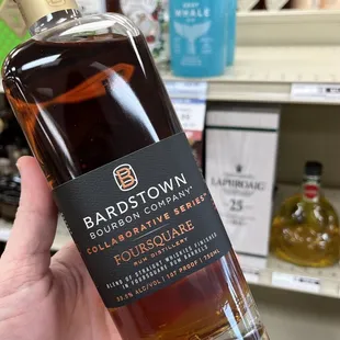 a hand holding a bottle of bourbon