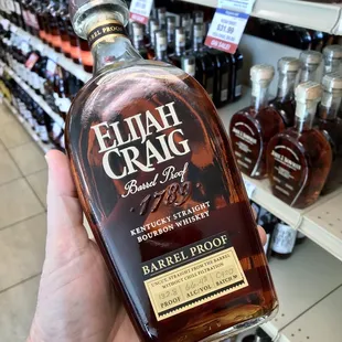 a hand holding a bottle of elijah craig bourbon
