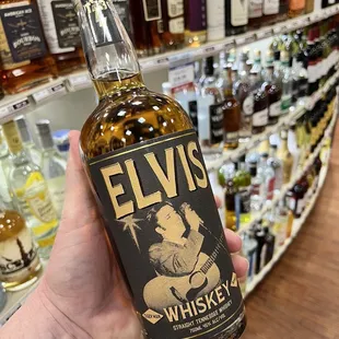 a hand holding a bottle of elvis whiskey