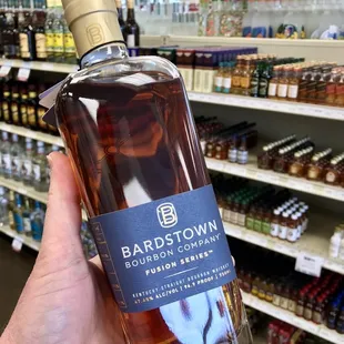 a hand holding a bottle of bourbon
