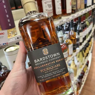 a hand holding a bottle of bourbon