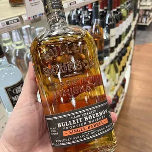 a hand holding a bottle of bourbon