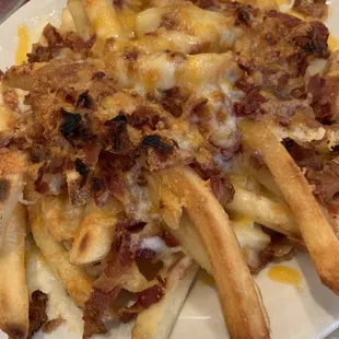 a plate of french fries with bacon and cheese