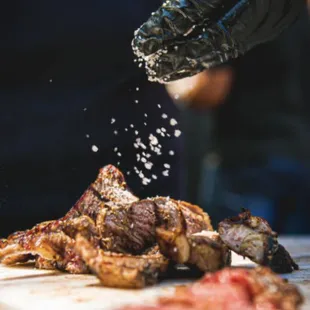 a chef sprinkling salt on a piece of meat