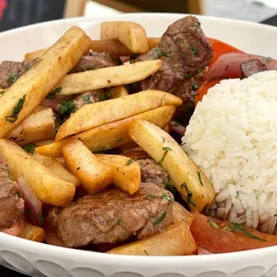 Lomo Saltado - Soft pieces of steak, tomato, onions mixed with french fries, served with rice