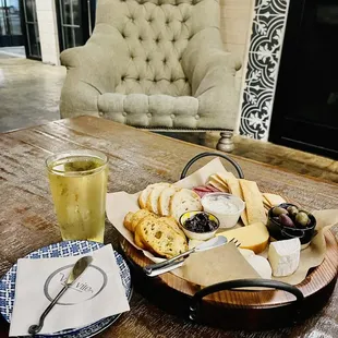 a plate of cheese, crackers, olives, and a glass of wine