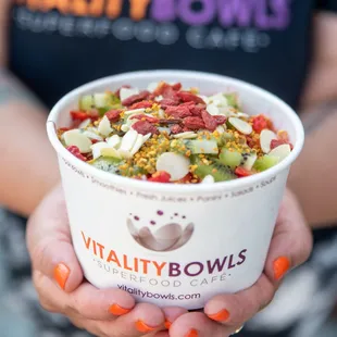 a woman holding a bowl of healthy bowls