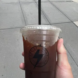 a hand holding a cup of iced coffee