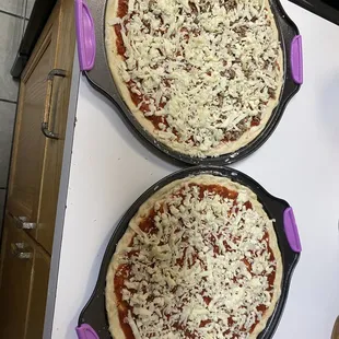 two uncooked pizzas