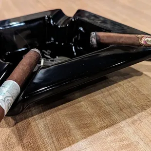 two cigars in a black ashtray