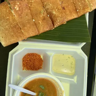 a tray of food including bread, soup, and sauce