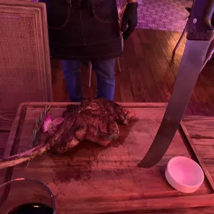 a steak on a cutting board with a large knife