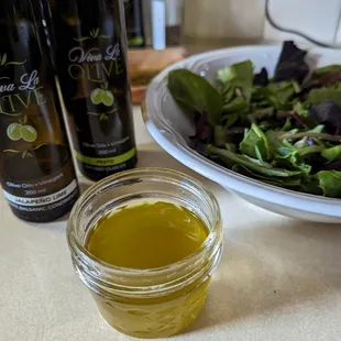 a bowl of salad and two bottles of olive oil