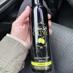 a hand holding a bottle of olive oil