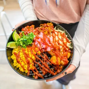 a person holding a bowl of mexican food