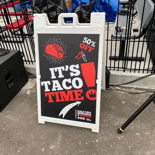 a taco time sign in front of a fence