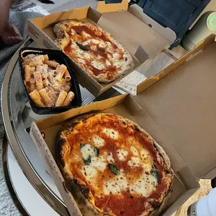 two pizzas in boxes on a table