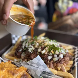 a person pouring sauce over a plate of food
