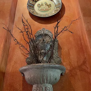 a wall with a vase and a plate on it