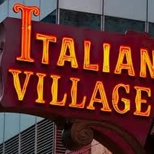 a red italian village sign in front of a tall building