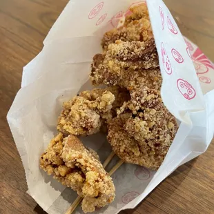fried chicken skewers in a paper bag
