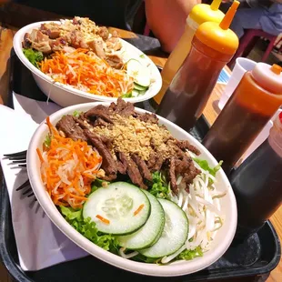 Beef salad bowl in front, chicken salad bowl in back. Sauces lined up on the side.