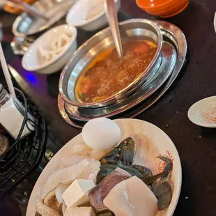 Tomato broth, plate of uncooked seafood and tofu about to be tossed in.  Remember to drink their broths too, not salty.