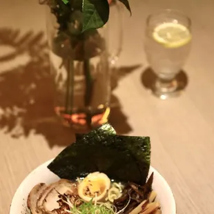 a bowl of noodles and a vase of flowers