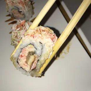 chopsticks holding a piece of sushi