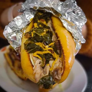 a person holding a sandwich wrapped in foil