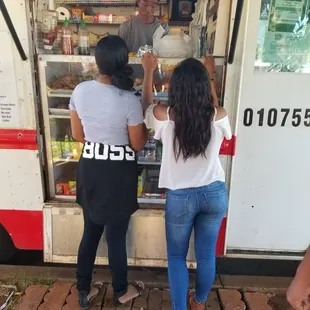 two women standing in front of a food truck