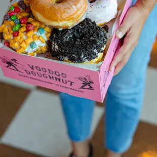 a woman holding a box of doughnuts