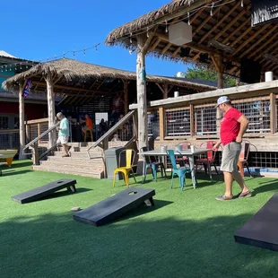 a man in a red shirt playing corn hole