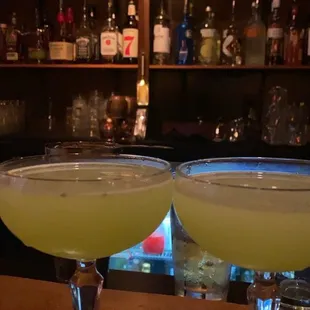 two cocktail glasses on a bar