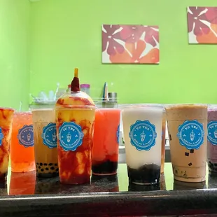 a variety of bubble teas lined up on a counter