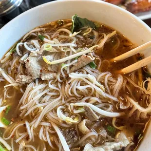 a bowl of soup with chopsticks